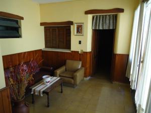 ein Wohnzimmer mit einem Stuhl und einem Tisch in der Unterkunft Hotel El Nogal in La Falda
