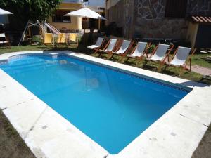 a large blue swimming pool with chairs and umbrella at Hotel El Nogal in La Falda +20 photos