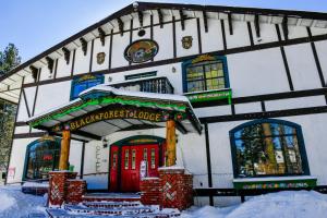 un bâtiment avec une porte rouge dans la neige dans l'établissement Black Forest Lodge, à Big Bear Lake