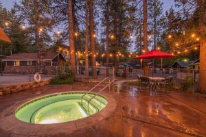 - un bain à remous dans une terrasse avec une table et un parasol dans l'établissement Black Forest Lodge, à Big Bear Lake