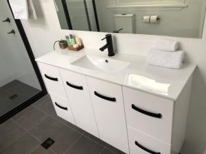 a bathroom with a white sink and a mirror at Vine Valley Inn in Cessnock +232 photos