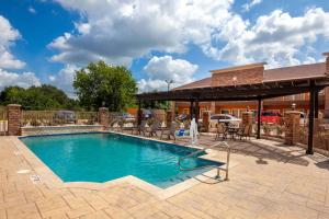 una piscina con patio y una casa en Super 8 by Wyndham Houston Northwest Cypress en Cypress