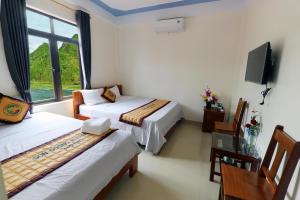 a hotel room with two beds and a tv at Son Doong Riverside in Phong Nha