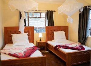 two twin beds in a room with a window at Wakawaka House in Arusha