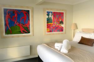 a bedroom with a bed with two paintings on the wall at SEA EAGLE COTTAGE Amazing views of Bay of Fires in Binalong Bay