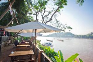 a group of tables and umbrellas next to a river at Phousi Guesthouse 2 in Luang Prabang