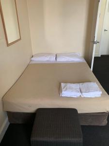a bed in a room with a white bedspread at National Hotel Toowoomba in Toowoomba
