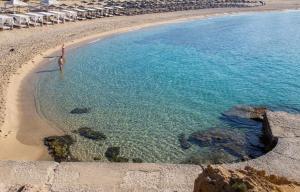 a person standing in the water on a beach at Green Bay in Limenaria