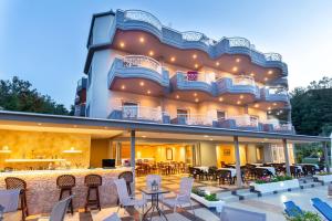 a large building with tables and chairs on a patio at Green Bay in Limenaria