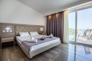 a bedroom with a large bed and a balcony at Green Bay in Limenaria