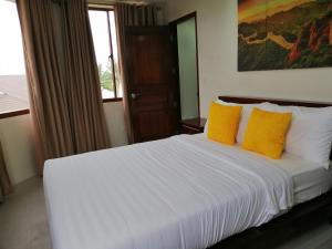 a bedroom with a white bed with yellow pillows at Nirvana Resort Puerto Galera in Puerto Galera