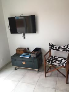 een kamer met een tv aan de muur met een stoel bij Les Terrasses de Bella Vista - Belle maison bord de mer in Saint-Vincent-sur-Jard