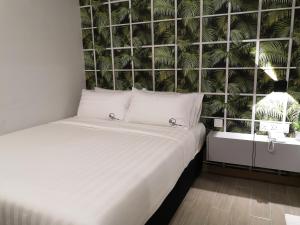 a white bed in a room with a wall with plants at Apex Boutique Hotel @ Bandar Sunway in Petaling Jaya