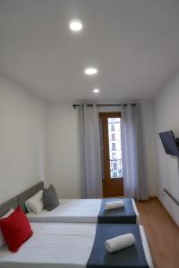 a bedroom with two beds with red and blue pillows at GS Latina in Madrid