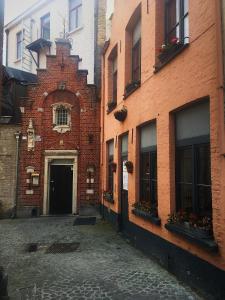 um beco com um edifício de tijolos com janelas e flores em City Flats by Lybeer Hotel Group em Bruges