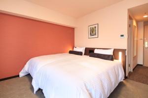 a bedroom with a large white bed with a red wall at Richmond Hotel Naha Kumoji in Naha