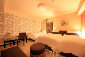 a hotel room with two beds and a table and chairs at Richmond Hotel Naha Kumoji in Naha
