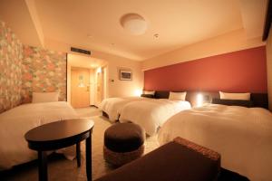 Habitación de hotel con 3 camas y mesa en Richmond Hotel Naha Kumoji, en Naha