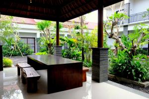 a table and bench in a courtyard with trees at The New Moon Seminyak in Seminyak
