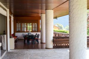 eine Terrasse mit einem Tisch und Stühlen auf einer Veranda in der Unterkunft Villa Mazzucco in Ponte nellʼAlpi