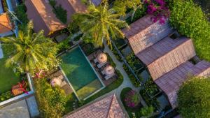 einen Blick über einen Garten mit Palmen und einem Pool in der Unterkunft United Colors of Gili in Gili Meno