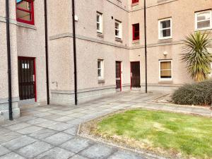 a large brick building with a grass yard in front of it at Dwellcome Home Ltd 2 Bed Aberdeen Apartment - see our site for assurance in Aberdeen