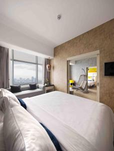 ジャカルタにあるYELLO ホテル ハーモ二の大きなベッドと鏡が備わるホテルルームです。