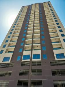 a tall brown building with blue windows at The Spot Residence in Juffair