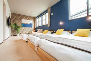 uma fila de camas num quarto com paredes azuis em UCHI Living stay NAKAJIMA park em Sapporo