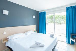 ein Schlafzimmer mit einem großen Bett und einem großen Fenster in der Unterkunft Zenitude Hôtel-Résidences La Tour de Mare in Fréjus