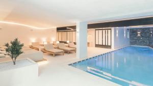 a swimming pool in a living room with a couch and chairs at Schlosshotel Ischgl 5-Sterne Superior in Ischgl