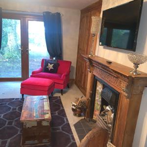 ein Wohnzimmer mit einem roten Stuhl und einem Kamin in der Unterkunft The Cottage, Grotton Hall, Lydgate, Saddleworth in Saddleworth