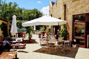 un patio con sombrilla blanca, mesas y sillas en Orlando in Chianti Glamping Resort, en Cavriglia