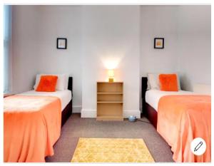 two beds in a room with orange sheets at Your Nottingham Vacation, Business Apart, Parking in Nottingham