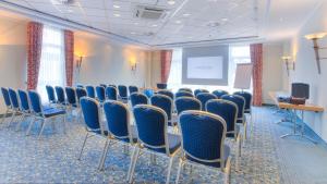 a conference room with blue chairs and a screen at Country Hotel Timmendorfer Strand in Timmendorfer Strand