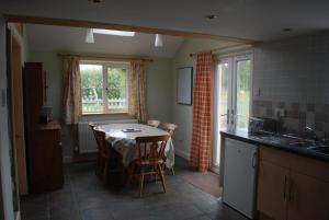 a kitchen with a table with chairs and a sink at Ty Gylfinir in Llandegla