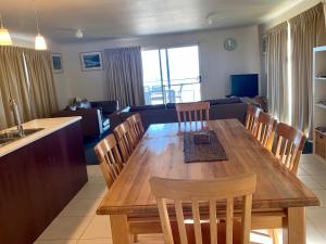 Bayview Beach House Apartment No 1 في كنغزكوت: غرفة طعام وغرفة معيشة مع طاولة وكراسي خشبية