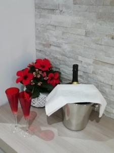 a bottle of wine and two glasses on a table with flowers at A casa di Zia Caterina in Zambrone