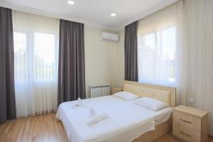 a bedroom with a white bed and two windows at Hotel Botanica in Chakvi