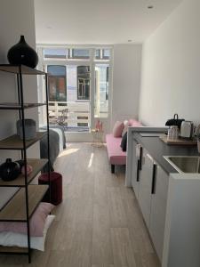uma cozinha e sala de estar com um sofá rosa em Payglop II em Alkmaar