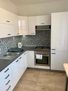 a kitchen with white cabinets and a stove and a sink at Apartman Skupovka in Most +17 photos