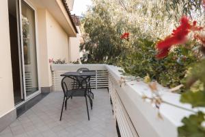 a table and chair on a balcony with flowers at Sicilia's Art Hotel & Spa in Acitrezza