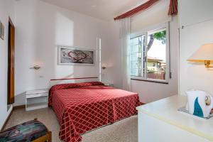 ein Schlafzimmer mit einem roten Bett und einem Fenster in der Unterkunft Hotel Marco Polo in Lignano Sabbiadoro + 97 Fotos
