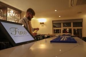a man standing behind a counter with a laptop computer at Fino Rooms in Felpham