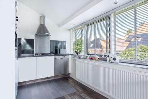 Den IlpAmsterdam Countryside met Airco ,Geweldig uitzicht, luxe keuken,wasmachine,droger,gratis fietsen的厨房设有白色的墙壁和窗户以及柜台。