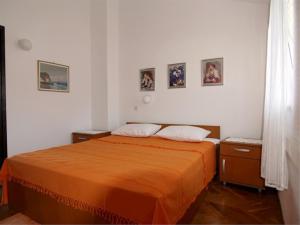 een slaapkamer met een bed met een oranje deken bij Bastinac 2 in Veli Lošinj