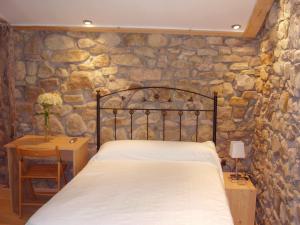 Un dormitorio con una cama y una pared de piedra. en Casa Rural Ortulane, en Urduliz