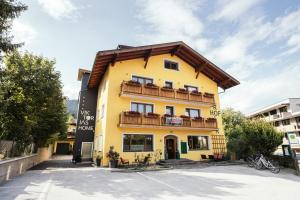 a yellow building with a wooden roof at Hotel VIKTORIAS HOME Kufstein in Kufstein