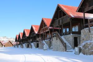 uma fila de casas com telhados vermelhos na neve em Cota 1500 - Chalé 51 - Penhas da Saúde em Penhas da Saúde