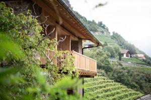 uma casa com uma varanda de madeira numa colina em Kristplonerhof em Bolzano